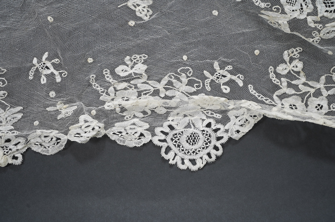 A late Edwardian hand bobbin lace Honiton and net wedding veil, approximately 248cm x 230cm. Condition - one corner has corner has been attached to a hair comb and damaged the netting.
